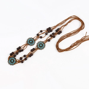 Close-up of woven brown cord belt with bronze flower charms and blue resin gemstones