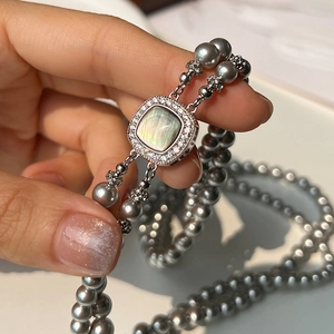 Detail of double-layer gray pearl necklace with square zircon and cat-eye stone clasp
