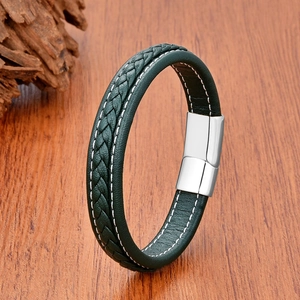 Close-up of a braided dark green leather bracelet with a silver magnetic metal clasp on wood