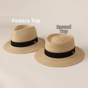 Close-up of raffia straw hats showing jazz top and round top designs with black ribbon
