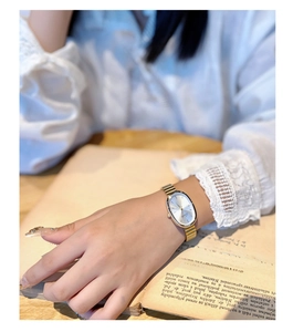 Close-up of elegant gold oval quartz watch on wrist with vintage aesthetic background