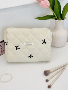 Quilted cotton cosmetic bag with black bow embroidery and secure zipper closure