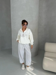 Detail view of women's white zip-up sweatshirt and grey joggers with street style print