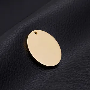 Polished gold round stainless steel disc pendant with hole on black leather background