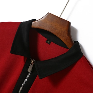 Detail of red polo shirt with black contrast collar, metal zipper, and fabric texture