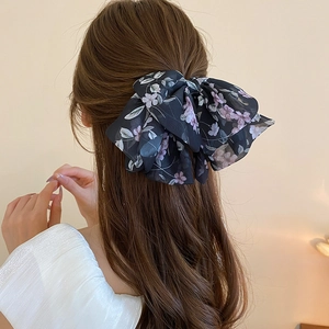 Dettaglio di una grande molletta per capelli a fiocco in chiffon floreale su modella