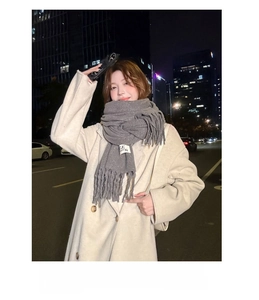 Close-up of gray fringed scarf worn by woman in a night city street photography scene