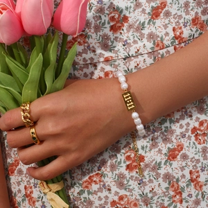 Detailed close-up of 11:11 gold charm bracelet with 18K hallmark and freshwater pearls