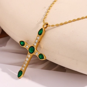 Vue macro du pendentif croix plaqué or 18K avec pierres vertes et micro zircons incrustés