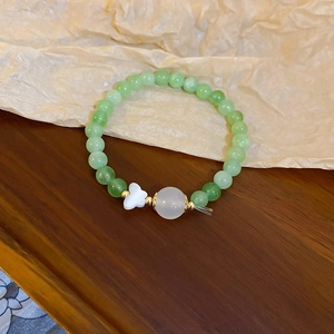 Détail macro du bracelet perlé avec papillon blanc et perles vert clair poli