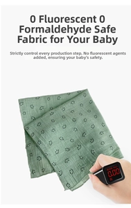Close-up of sage green cotton baby bib with smile prints and safety test detail