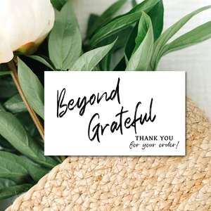 Detail of pink thank you card with 'Beyond Grateful' text on a textured beige surface