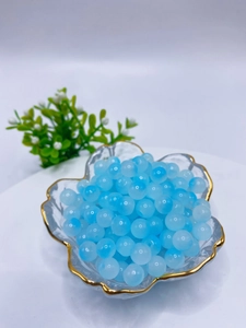 Macro shot of 8mm translucent blue glass beads for DIY jewelry making in a glass bowl