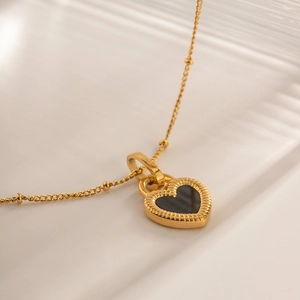 Macro shot of 18K gold plated heart pendant with black inlay and beaded chain details