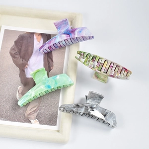 Flat lay of colorful marble pattern hair claws in purple, green, and gray resin