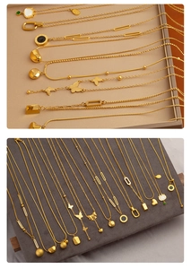 Macro detail of various gold necklaces featuring butterfly, heart, and ring pendants