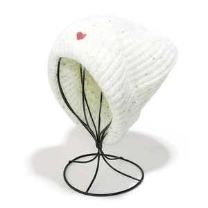Detailed close-up of white chunky knit beanie with a red heart embroidery on the cuff