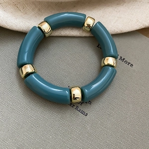 Close-up of teal acrylic bamboo link bracelet with polished gold metal spacers