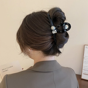Detail of a black acrylic hair claw clip with faux pearl and rhinestone on hair
