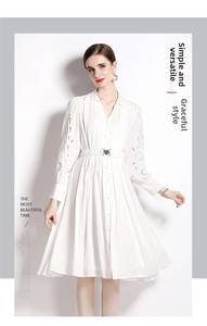 Détail d'une robe blanche brodée à manches longues avec col en V et boutons avant