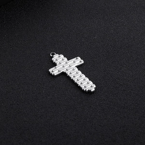 Pendentif croix en acier inoxydable argenté poli sur un fond noir texturé pour homme