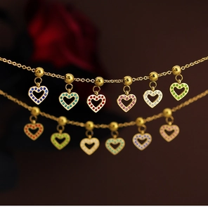 Close-up of golden hollow heart pendants with colorful crystals on elegant chains