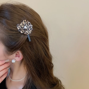 Gros plan d'une pince à cheveux fleur léopard avec perle centrale sur un mannequin