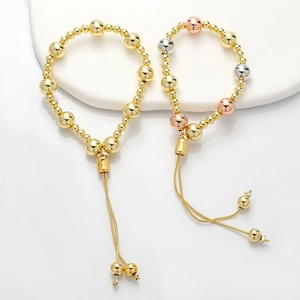 Detail of adjustable beaded bracelets in gold and tri-color finishes with tassel charms