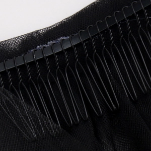Detailed close-up of a black metal hair comb attachment sewn onto soft bridal veil mesh