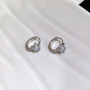 Gros plan des boucles d'oreilles étoile en argent avec zircons sur fond blanc