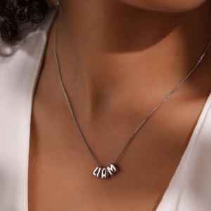 Dettaglio della collana in metallo argento con ciondoli a lettere DIY che formano LIAM