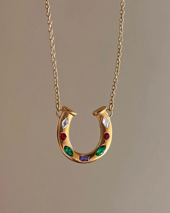 Detailed close-up of a horseshoe pendant with multi-color zircon stones on a gold chain