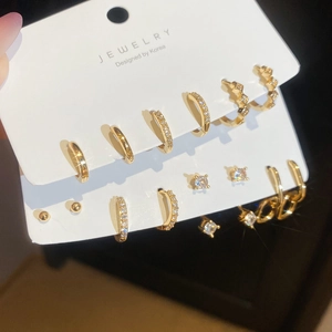 Dettaglio di un set di orecchini placcati in oro con zirconi su cartoncino bianco