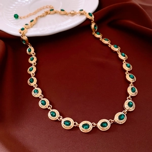 Macro detail of vintage gold chain with oval green gemstones on elegant red silk background