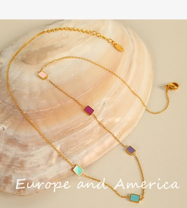Detail of colorful enamel rectangular charms on a gold titanium steel necklace on a shell