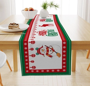 Detail of Christmas linen table runner with snowman and reindeer patterns on wooden table