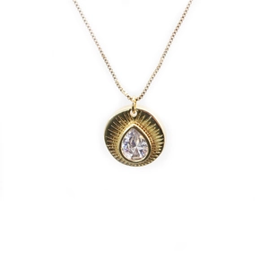 Macro detail of gold plated necklace with teardrop zircon and sunburst pendant