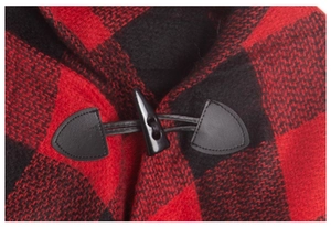 Detail of red and black plaid cape featuring classic horn button and leather closure