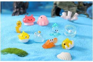 Macro shot of mini resin ocean animals like crab and octopus on blue sand background