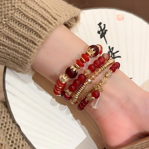 Detail of multi-layer beaded bracelet set with red agate beads and golden accents