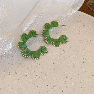Macro detail of leaf-shaped green enamel C-shaped hoop earrings with gold trim