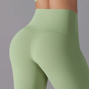Detail of high-waist yoga pants with butt-lifting seams and matte elastic green fabric