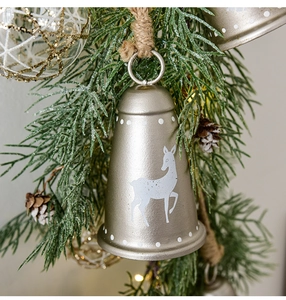 Nahaufnahme der goldenen Weihnachtsglocke aus Metall mit Rentier-Muster und Juteseil-Hänger