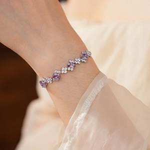 Detailed view of silver charm bracelet with purple zircon floral pattern and white stones