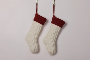 Detail of cable knit texture on ivory Christmas stockings with red cuffs and hanging loops