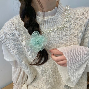 Detail showing a light green mesh camellia flower clip on a model's braided hairstyle