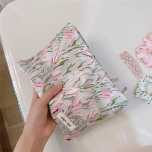 Detail of a floral tulip canvas cosmetic bag with simple wish label being held by hand
