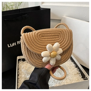 Dettaglio della borsa in paglia intrecciata con margherita bianca in confezione regalo