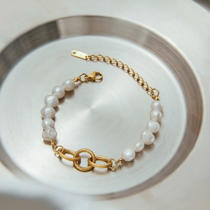 18k gold plated stainless steel bracelet with white baroque pearls on a silver tray