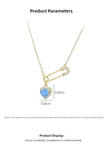 Detail of gold safety pin necklace with micro-pave zircon heart and blue gemstone charm